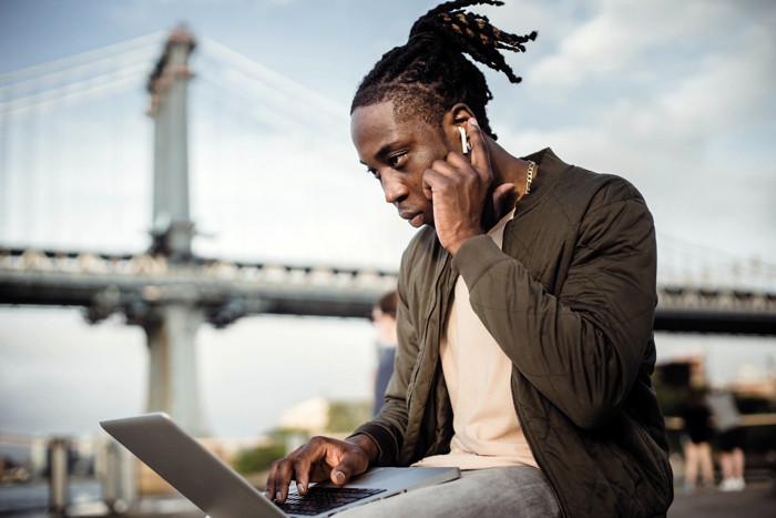 man on laptop and phone, outdoors