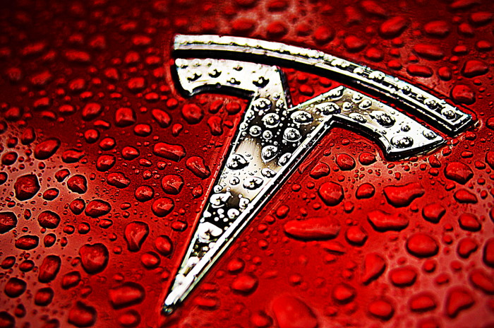 tesla logo on red background with water drops